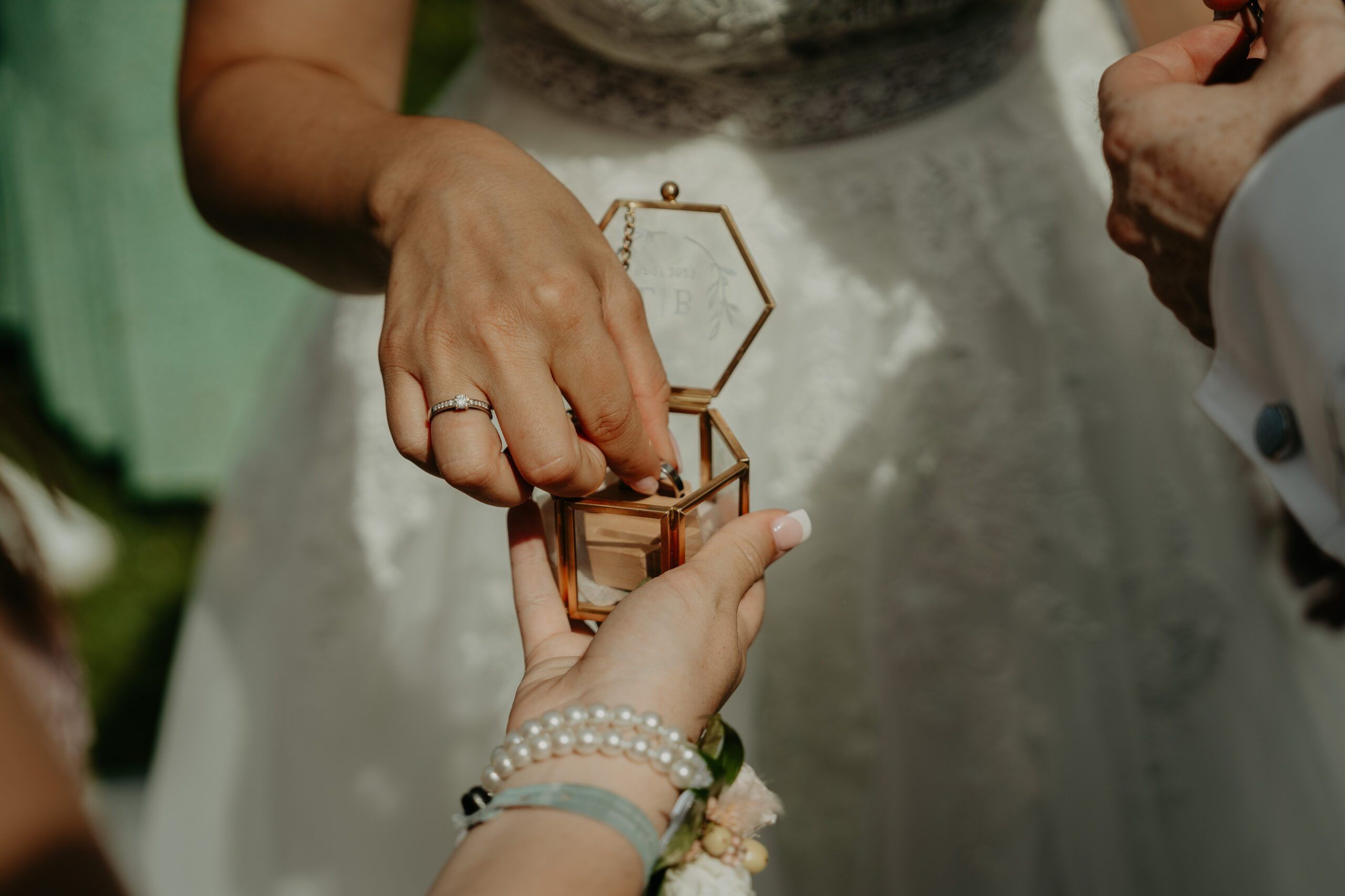 La mariée prend une alliance dans une petite boîte de verre.