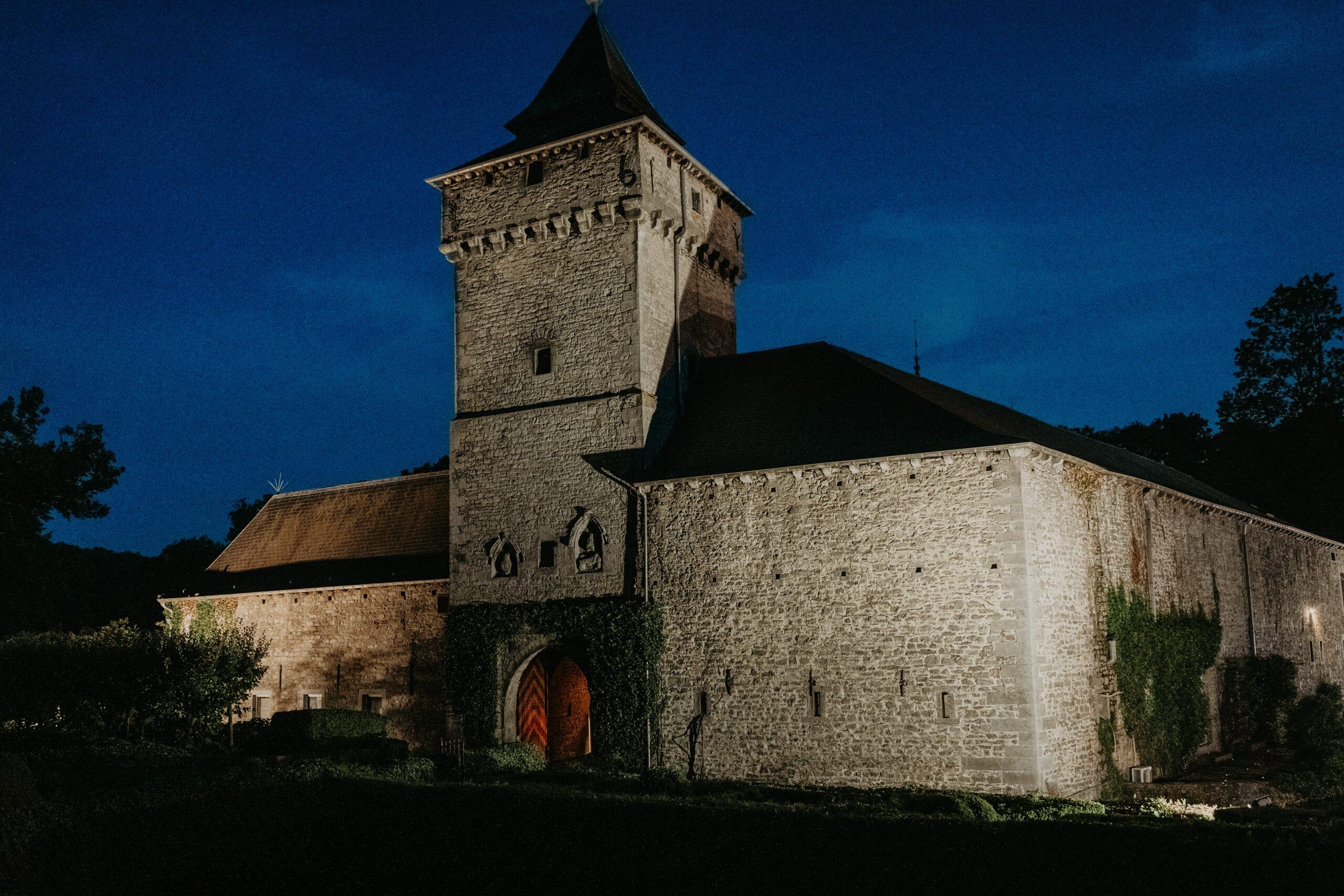 Un château et sa tour à l’heure bleue, aux fenêtres éclairées.
