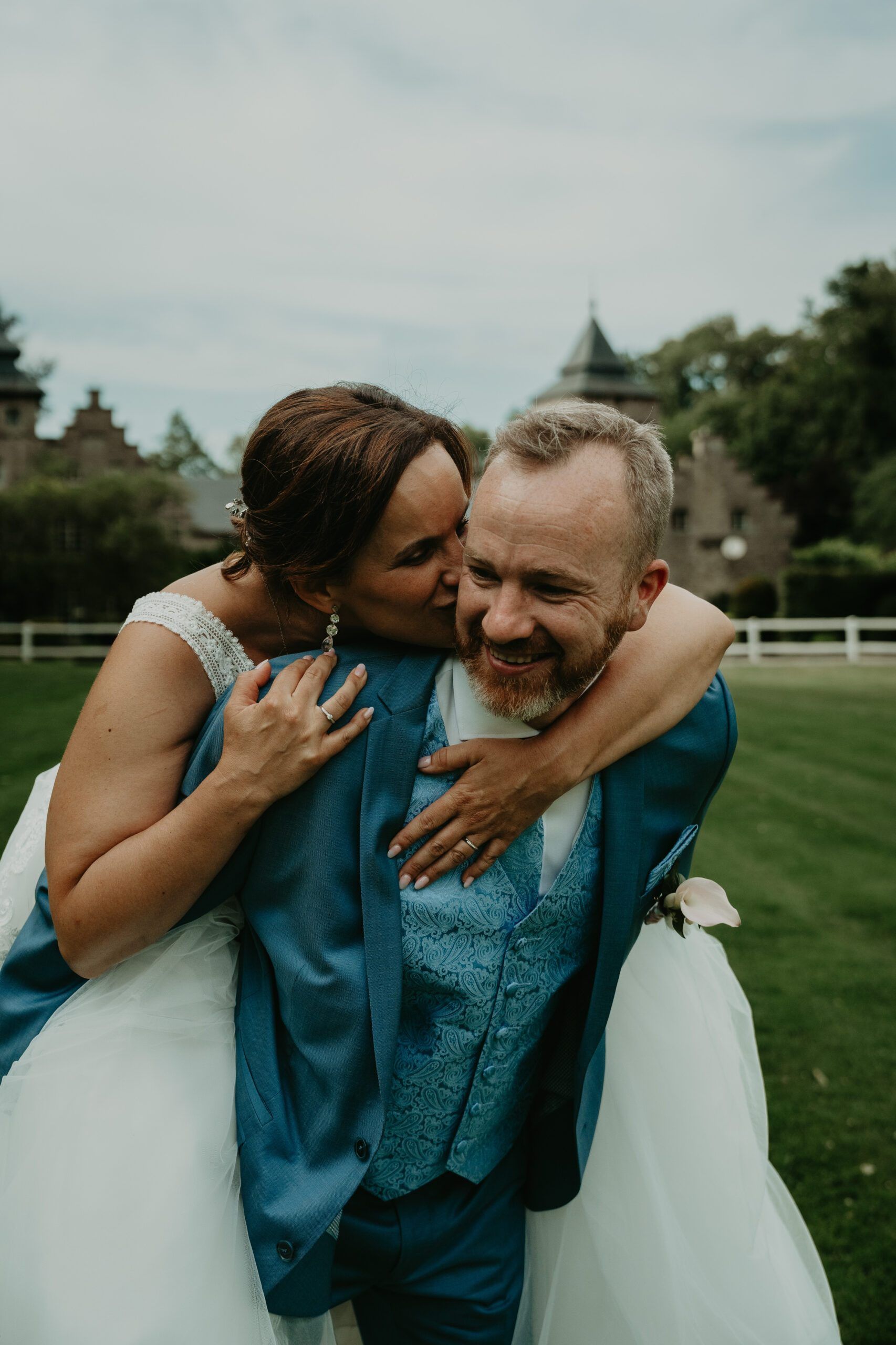 La mariée enlace le marié par-derrière ; tous deux éclatent de rire.