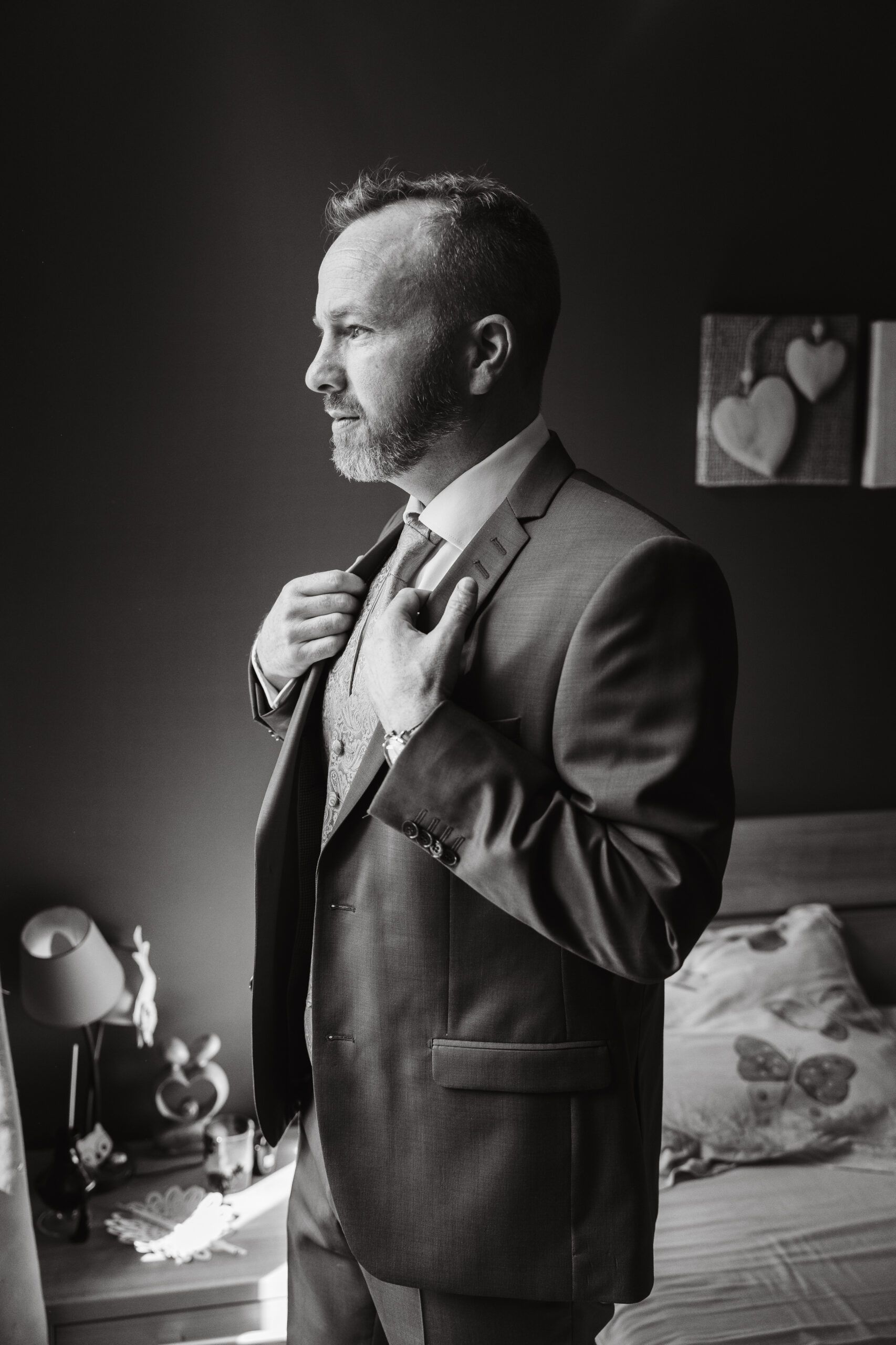 Benoît ajuste sa veste, en noir et blanc.