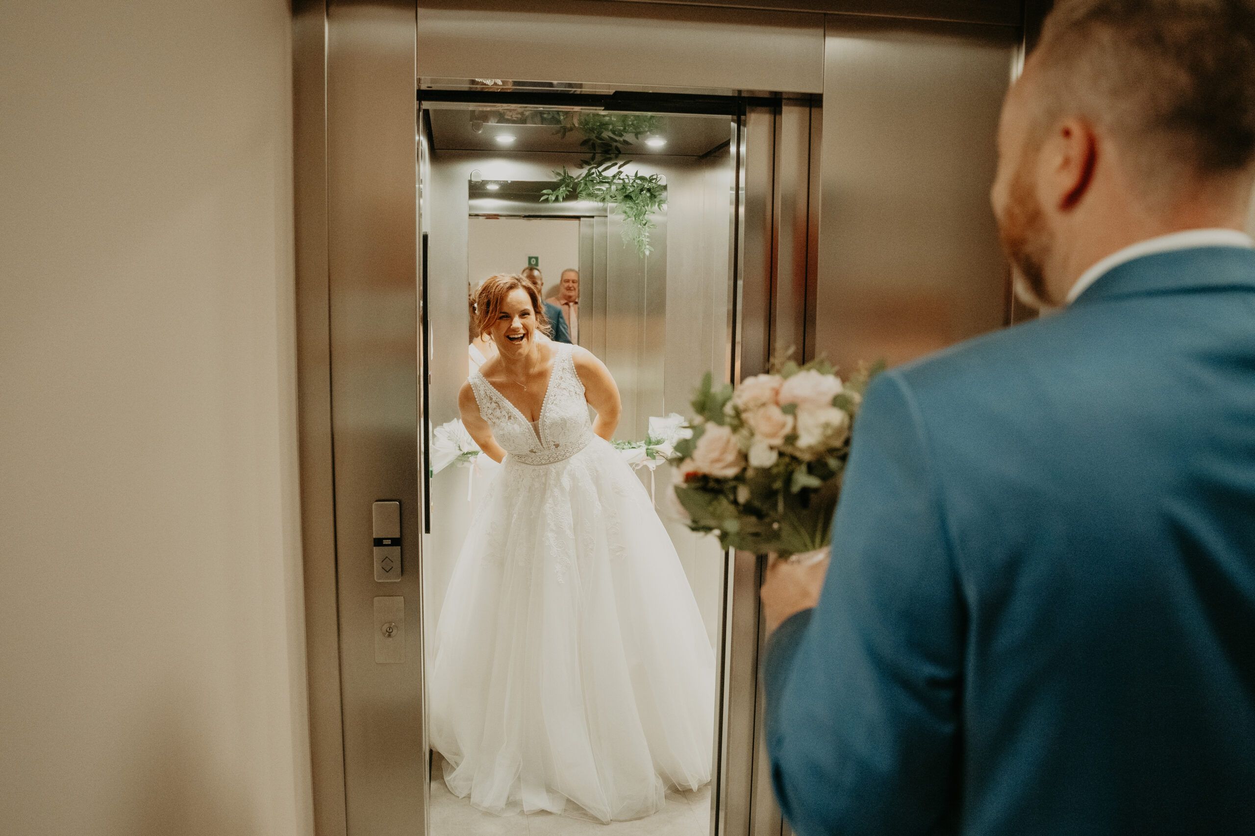 Les portes de l’ascenseur s’ouvrent sur Laura ; Benoît l’attend, de dos.