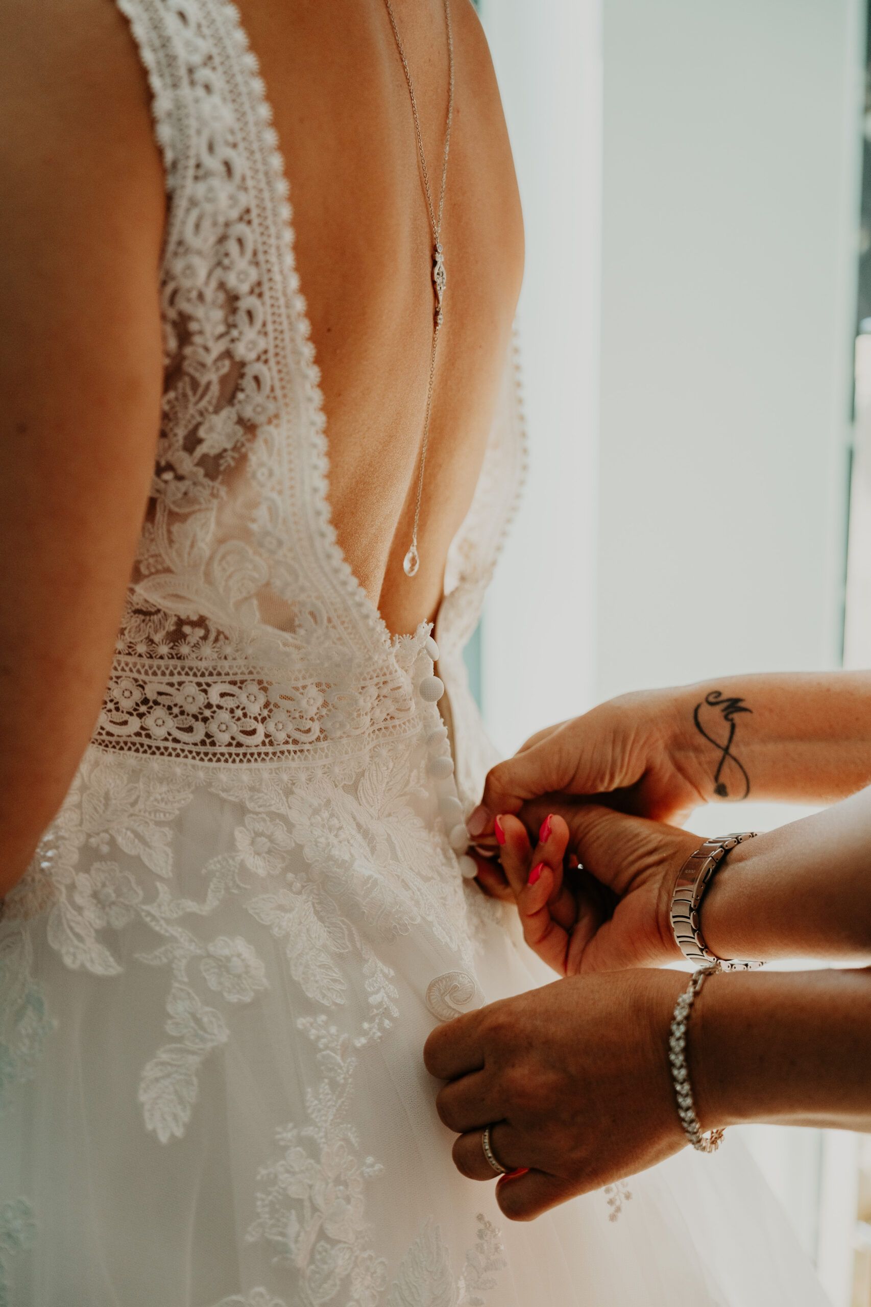 Des mains ferment la robe de dentelle dans le dos de Laura.
